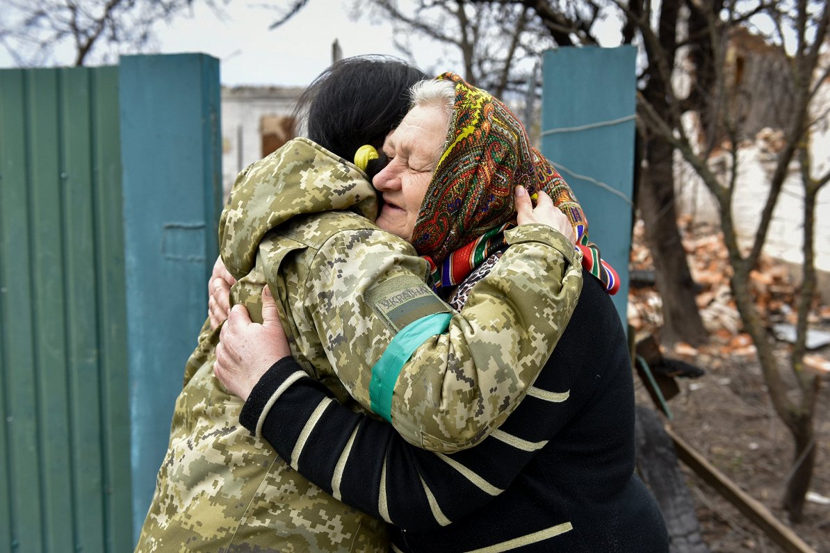 62 gadus vecā Ļuba no Andrijivkas ciema Kijivas pievārtē apskauj Ukrainas zemessardzes pārstāvi. 202...