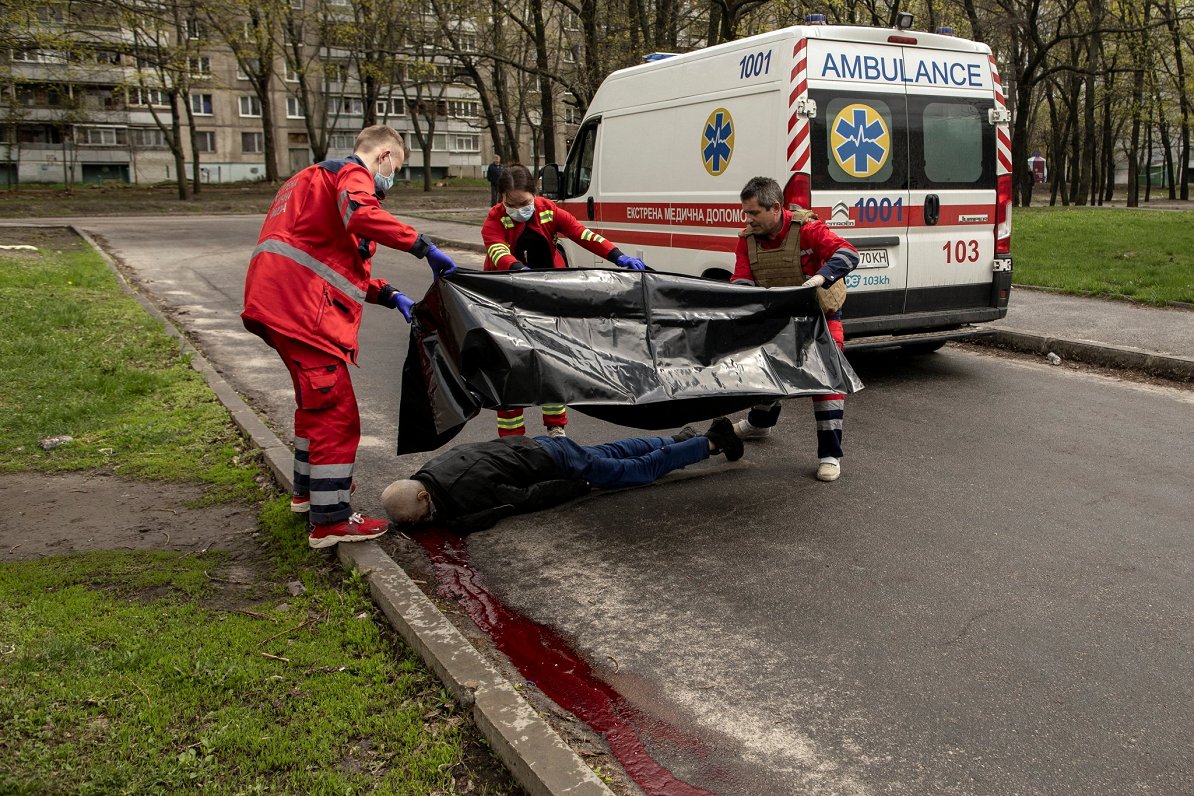 Ukrainas austrumu pilsētā Harkivā mediķi savāc Krievijas uzbrukumā nogalināta vīrieša līķi