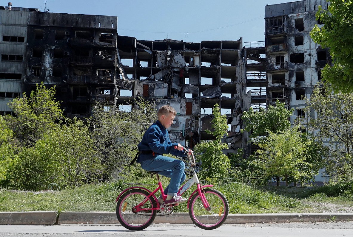 Ukraiņu zēns ar velosipēdu izpostītās Mariupoles pilsētas ielās