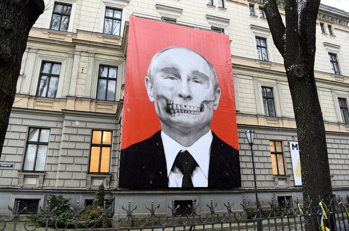 Plakāts ar Vladimira Putina attēlojumu uz žurnāla “IR” vāka un pretī Krievijas vēstniecībai