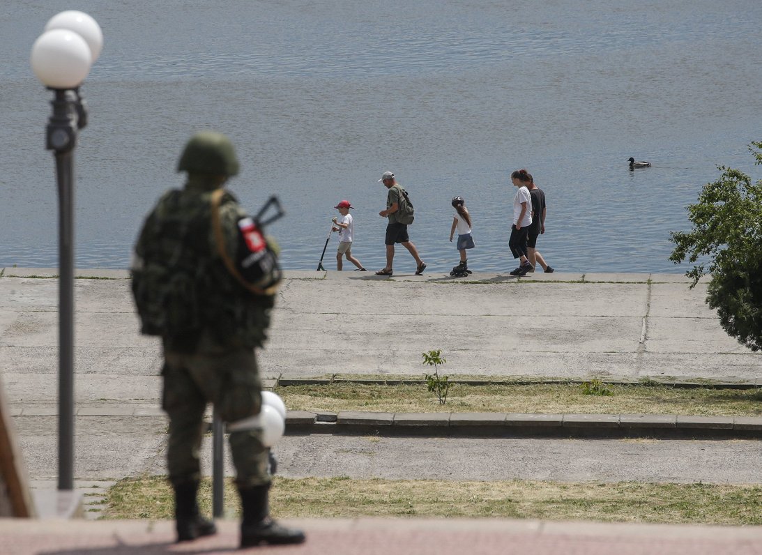 Krievijas spēku karavīrs vēro okupētās Hersonas pilsētas iedzīvotājus. Attēls ilustratīvs.