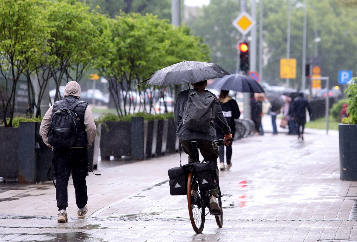 Cilvēki ar lietussargiem Satekles ielā.