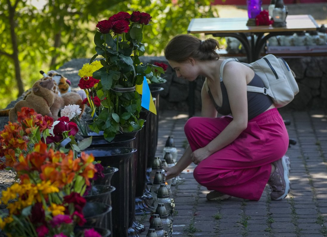 Ukrainas pilsētā Kremenčukā sieviete aizdedzina svecīti, pieminot Krievijas raķešu uzbrukumā nogalin...