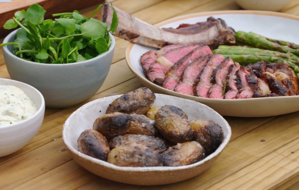 Steiku pasniedz ar oglēs ceptiem kartupeļiem un grilētiem sparģeļiem.