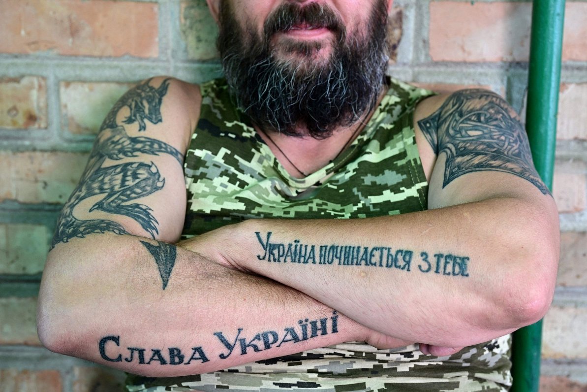 Ukrainas karavīrs ar tetovējumiem, kas vēsta &quot;Slava Ukrainai!&quot; un &quot;Ukraina sākas ar T...