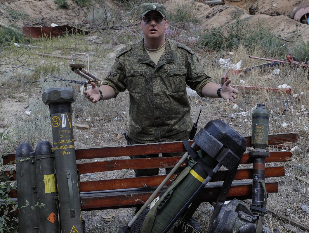 Prokrievisko spēku karavīrs rāda ukraiņiem atņemto militāro aprīkojumu.