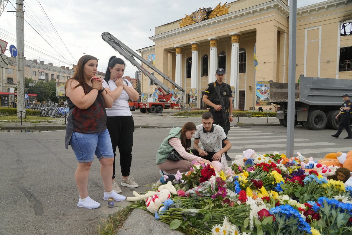 Cilvēki novieto ziedus Vinnicas centrā, kur ceturtdien Krievijas raķešu uzbrukumā gāja bojā vairāk n...