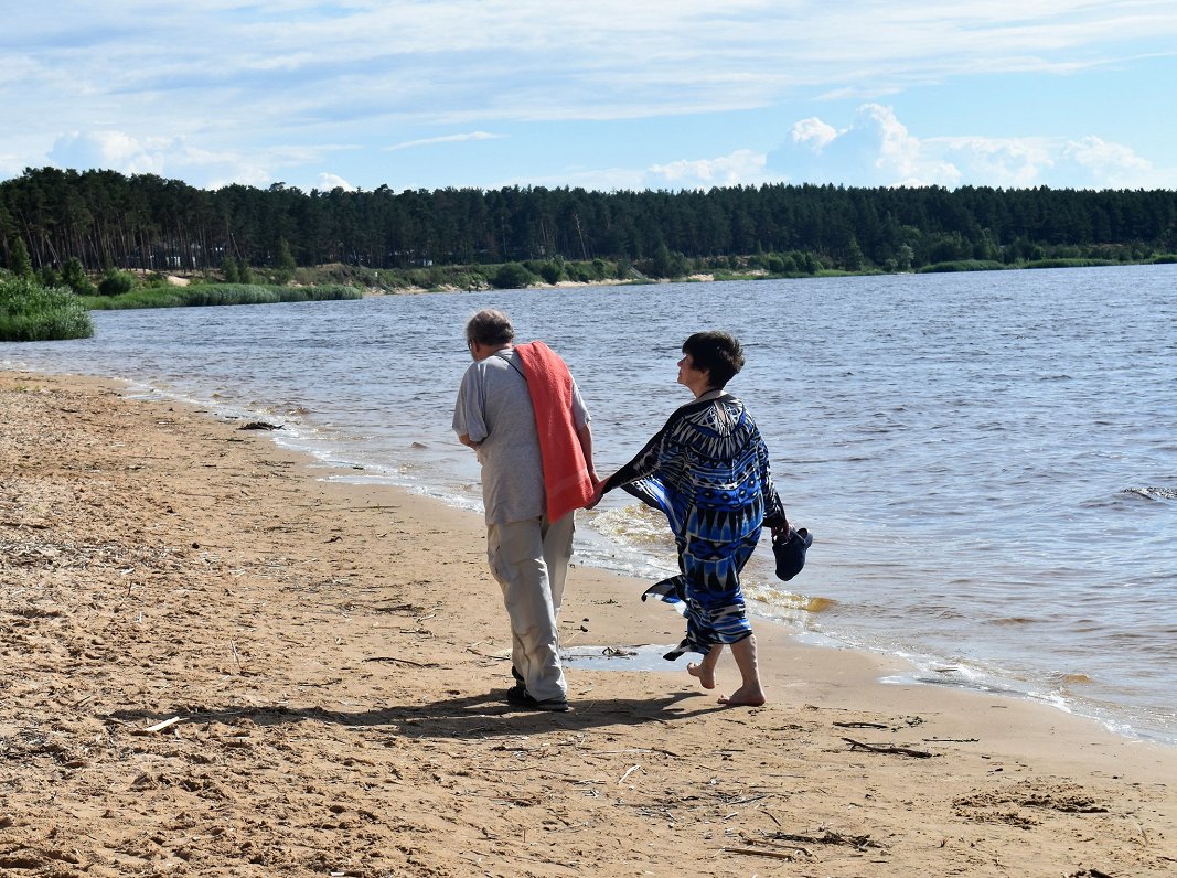 Couple walk on the beach at Vārnukrogs