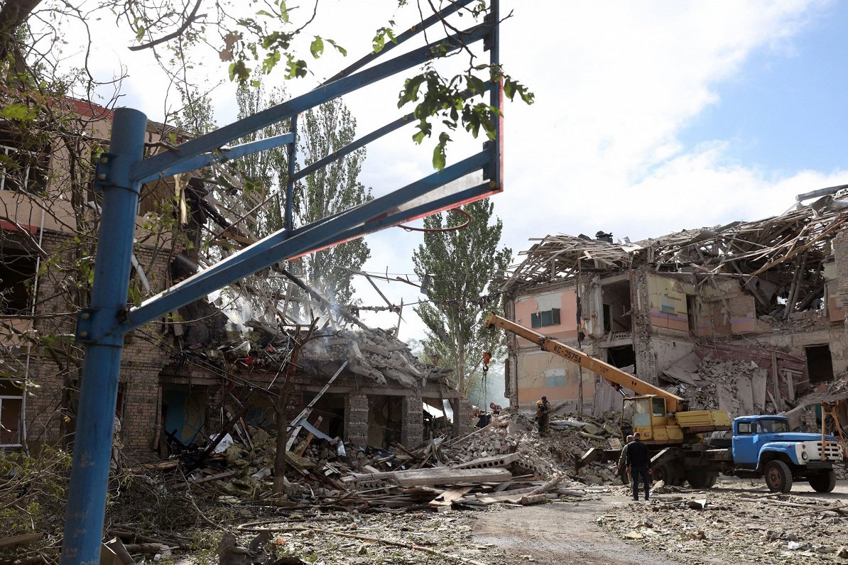 Украинские спасатели автокраном вывозят обломки здания школы, сильно поврежденного в результате обст...