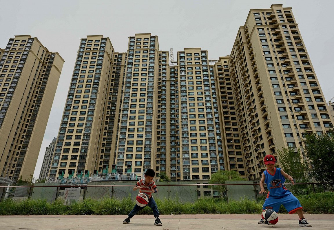 Bērni spēlē basketbolu pie daudzdzīvokļu nama Pekinā