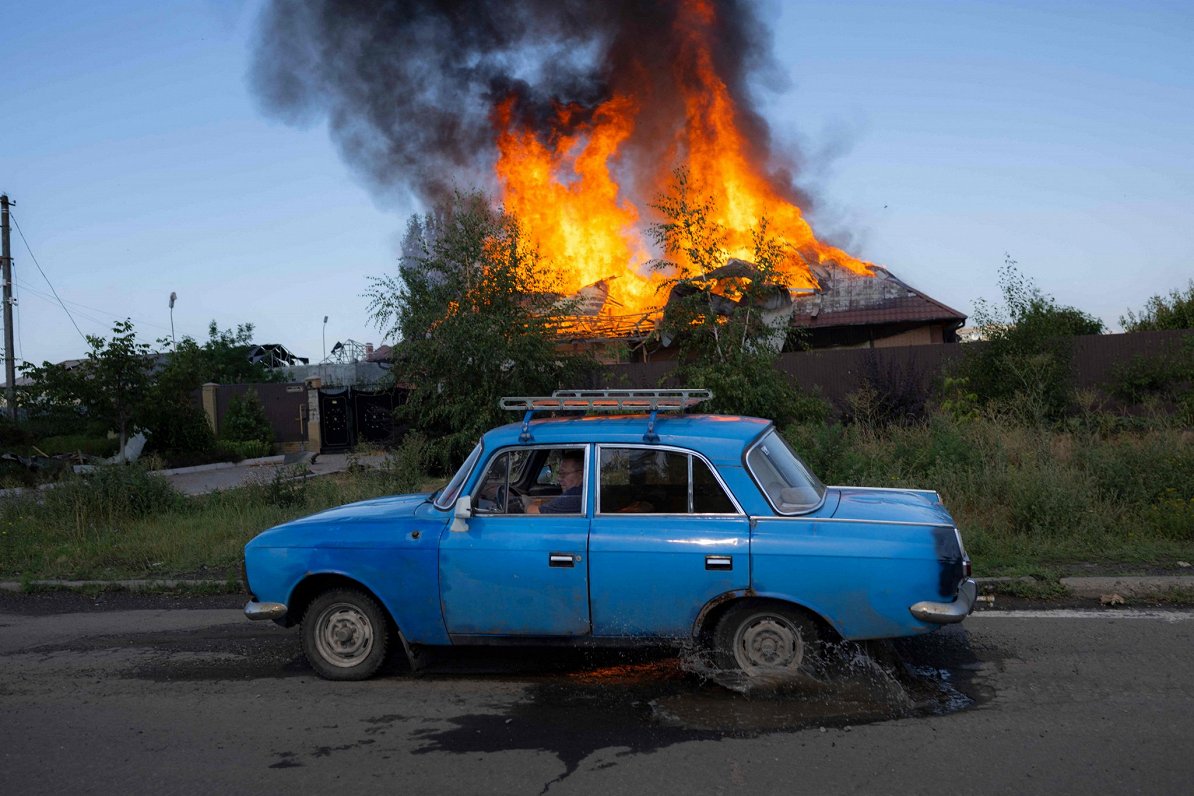 Ukrainas austrumos vīrietis ar &quot;Moskvič&quot; automašīnu brauc gar karadarbībā cietušu māju