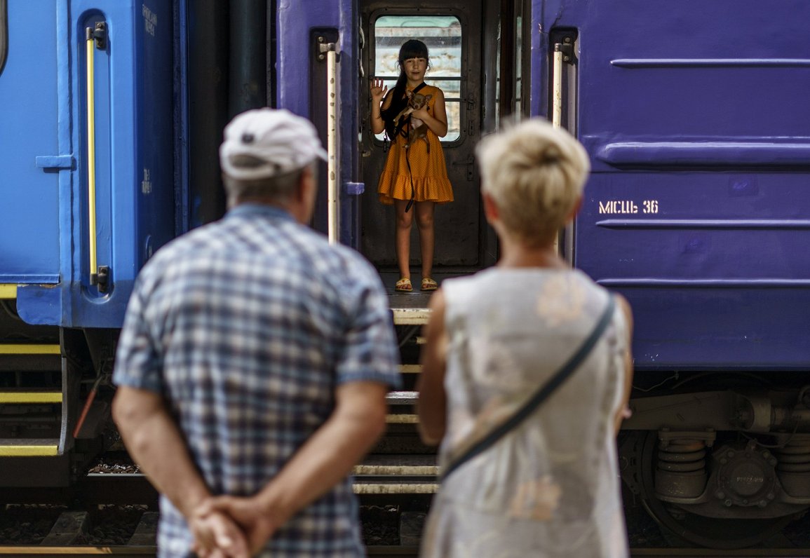 Meitene ar suni atvadās no saviem vecvecākiem, sēžoties evakuācijas vilcienā, kas viņu no Doneckas a...
