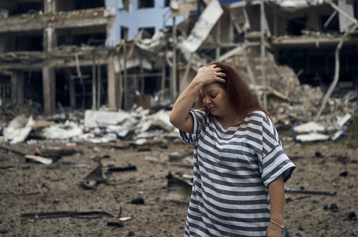 Sieviete pie apšaudēs izpostītām ēkām Ukrainas pilsētā Mikolajivā