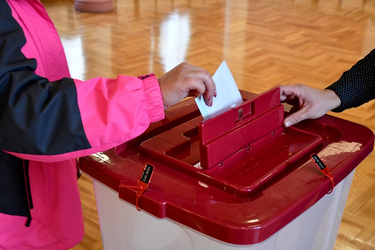 Vēlētājs liek savu biļetenu vēlēšanu urnā.