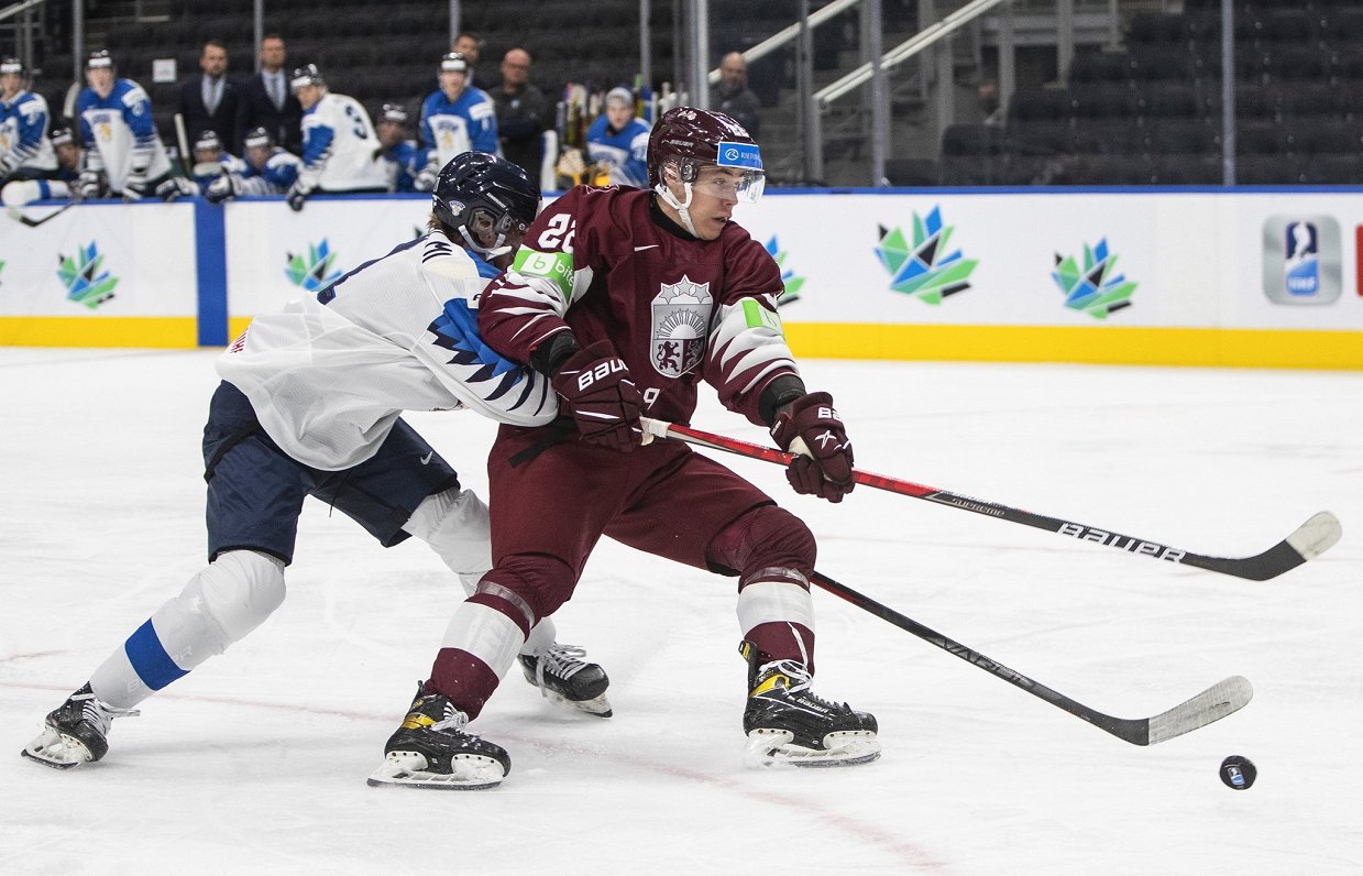 Latvijas hokejists Sandis Vilmanis un soms Aleksi Heimosalmi cīnās par ripu U-20 pasaules čempionāta...