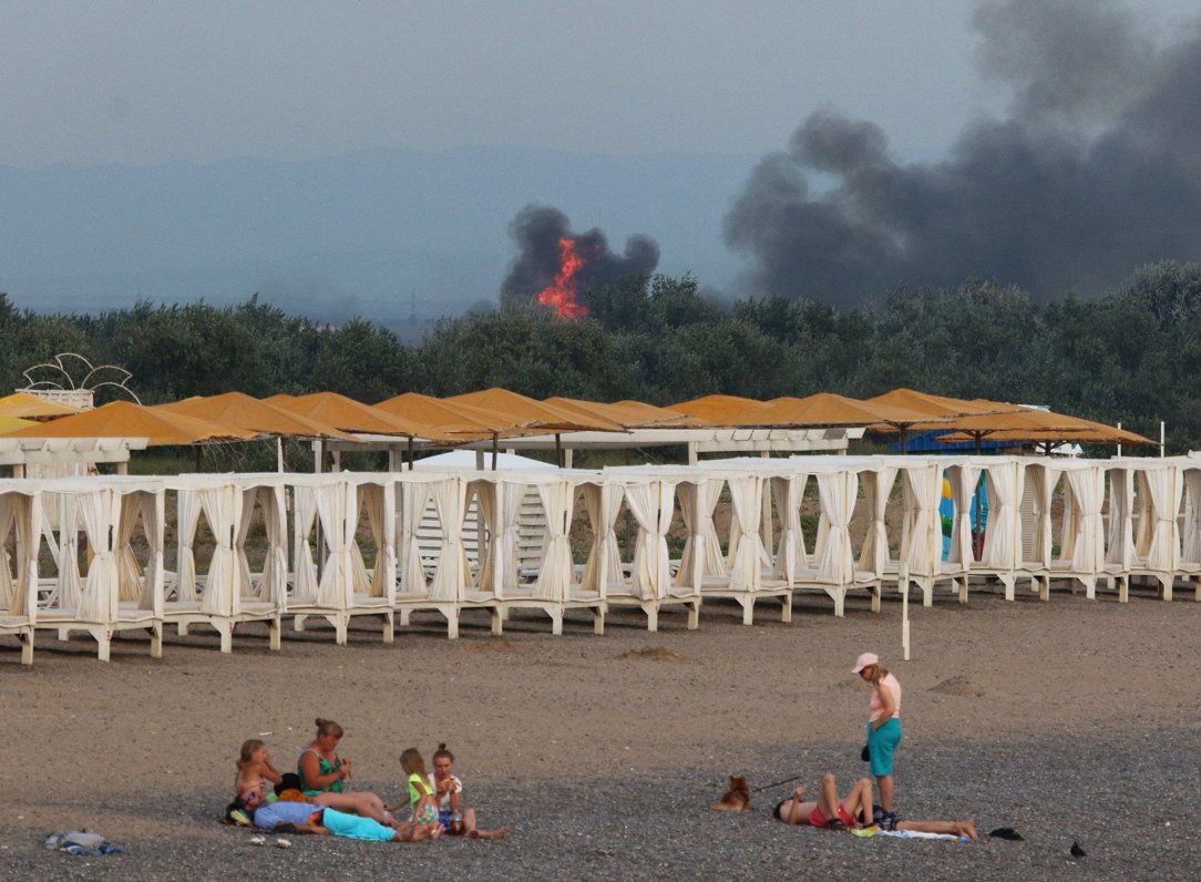 Atpūtnieki pie Novofedorivkas ciema Krievijas okupētajā Krimā. Fonā redzams ugunsgrēks Krievijas kar...