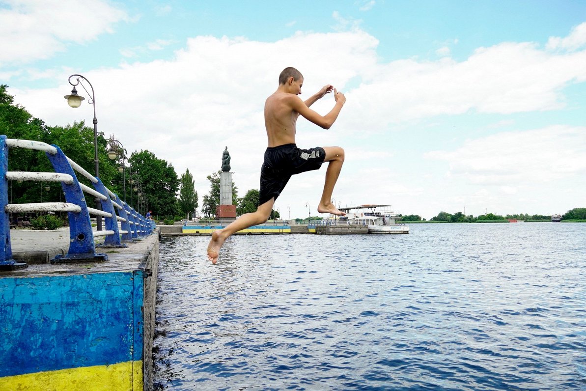 Jaunietis peldas Dņepras upē pie Krievijas spēku okupētās Hersonas pilsētas, 2022. gada jūlijs