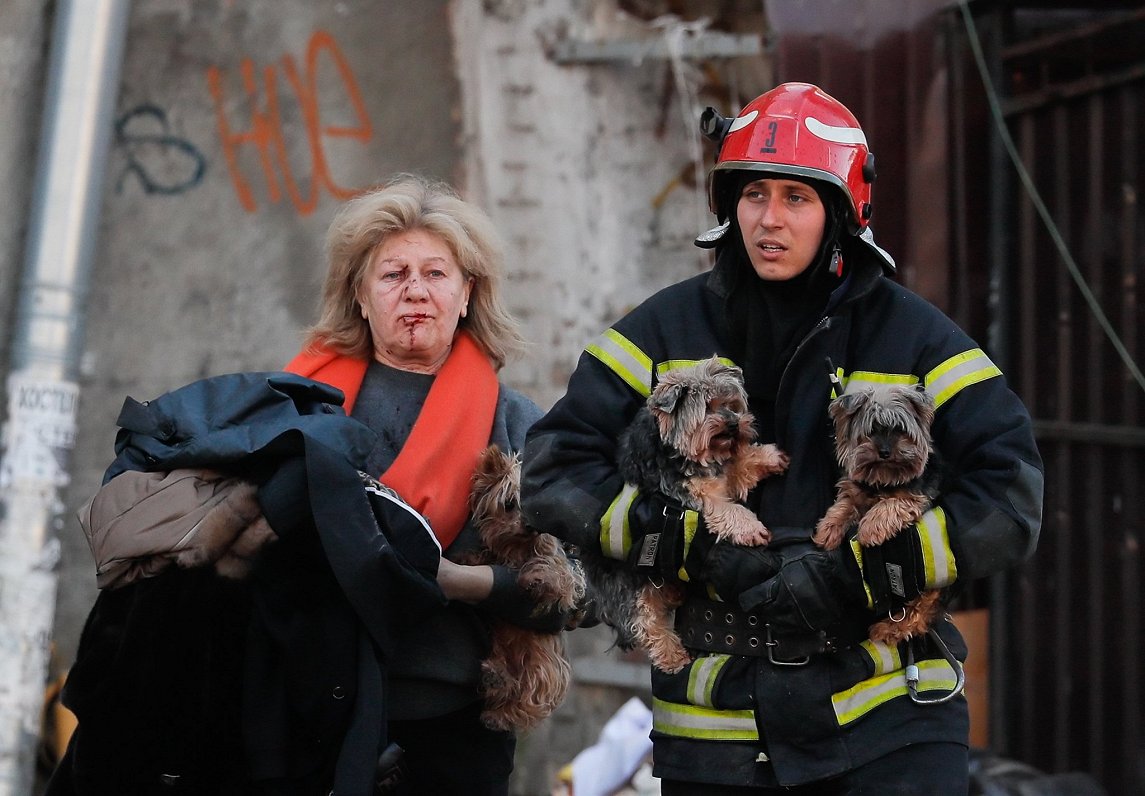 Ukrainas galvaspilsētā Kijivā glābējs palīdz ievainotai sievietei un viņas suņiem