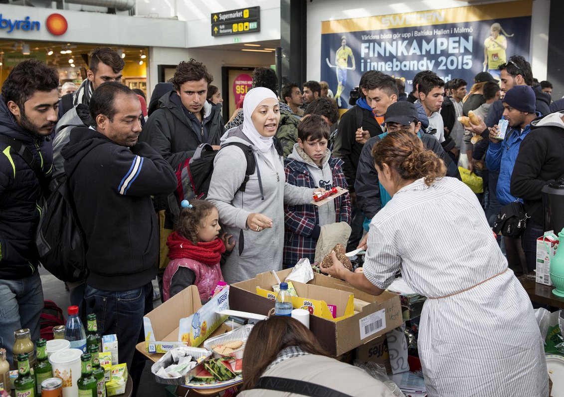 Zviedru brīvprātīgie izsniedz pārtiku migrantiem, kas ieradušies Zviedrijas pilsētā Malmē, 2015. gad...