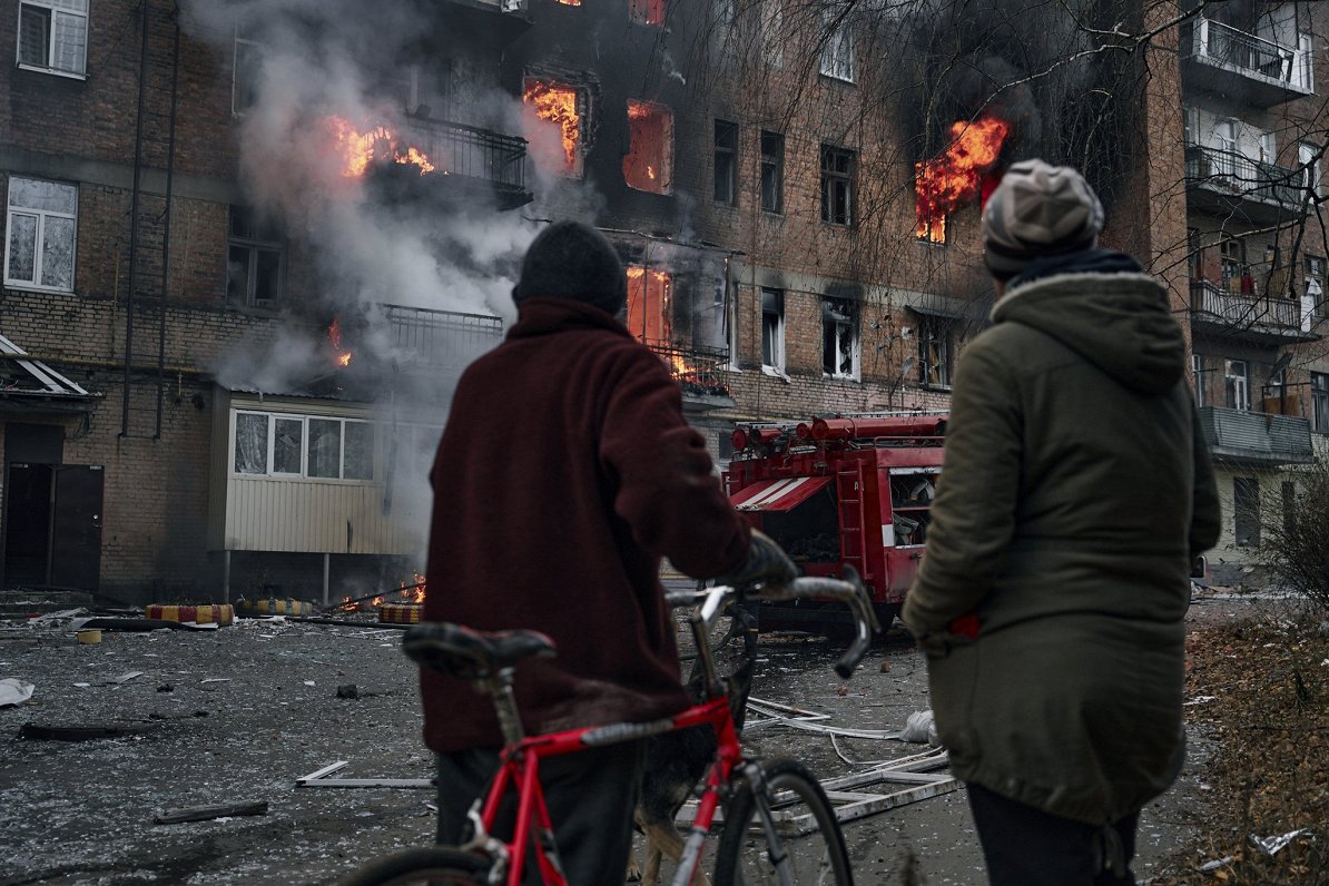 Ukrainas pilsētas Bahmutas iedzīvotāji pie mājas, kas aizdegusies pēc Krievijas spēku veiktās apšaud...