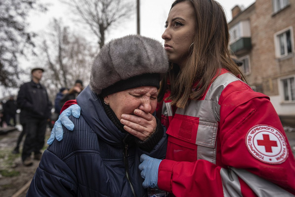 Sarkanā Krusta darbiniece mierina sievieti, kuras māja izpostīta Krievijas raķešu triecienā Ukrainas...