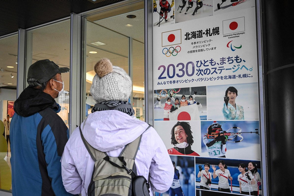 Saporo iedzīvotāji aplūko 2030.gada ziemas olimpisko spēļu reklāmas plakātu