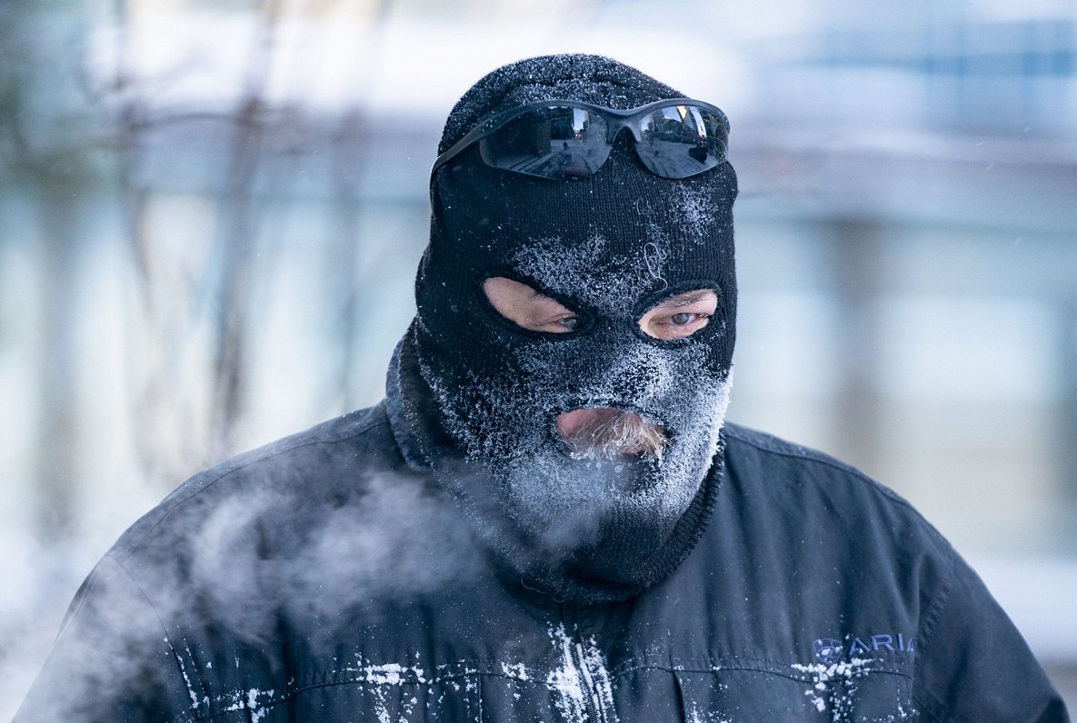 ASV ziemeļu pilsētā Mineapolisā vīrietis ar sejas masku lielā aukstumā tīra sniegu