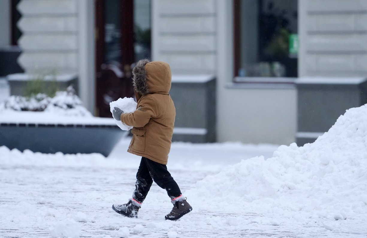 Bērns ar sniega piku rokās Rātslaukumā.