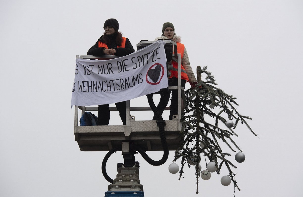 Berlīnē klimata aktīvisti nozāģējuši pie Brandenburgas vārtiem uzstādītās Ziemassvētku egles galotni...