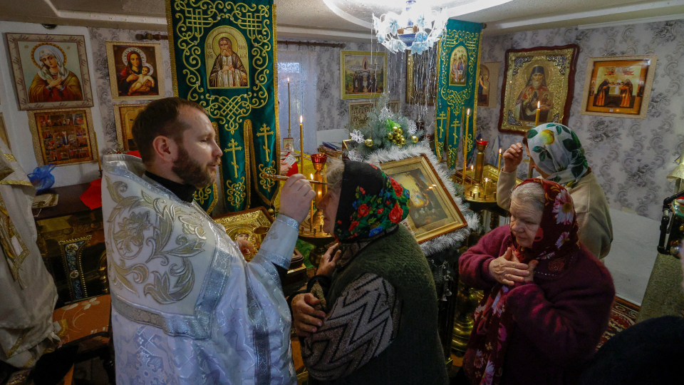 В оккупированной РФ Волновахе верующие подходят к священнику для елеопомазания во время рождественск...