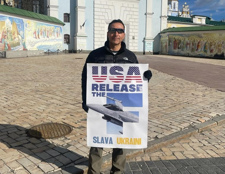 Piketētājs ar plakātu rokā, aicinot ASV “atbrīvot F-16 iznīcinātājus”