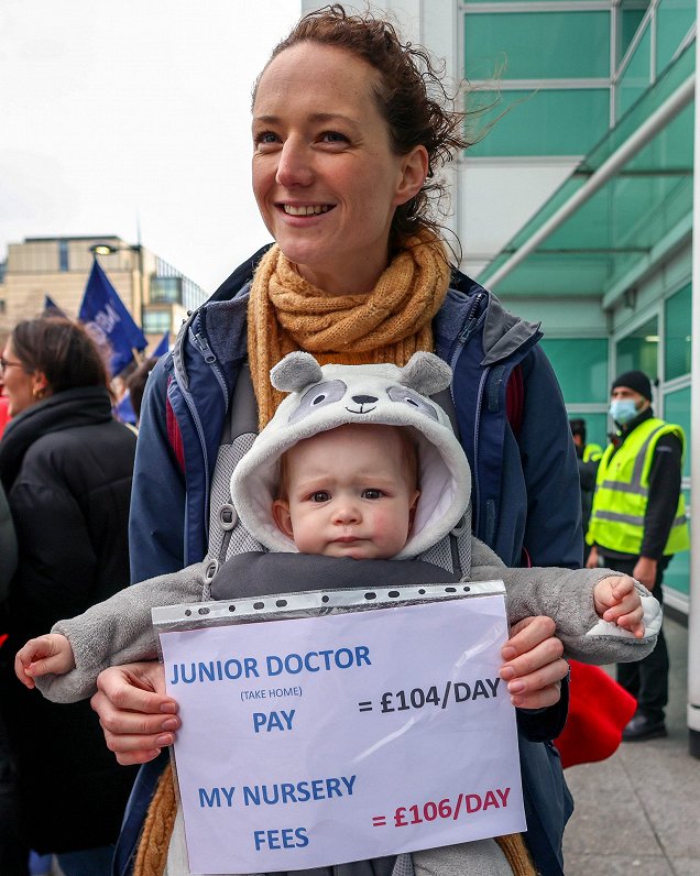 Mediķu streika dalībniece Londonā ar plakātu &quot;Jaunais ārsts saņem 104 mārciņas (118 eiro) dienā...