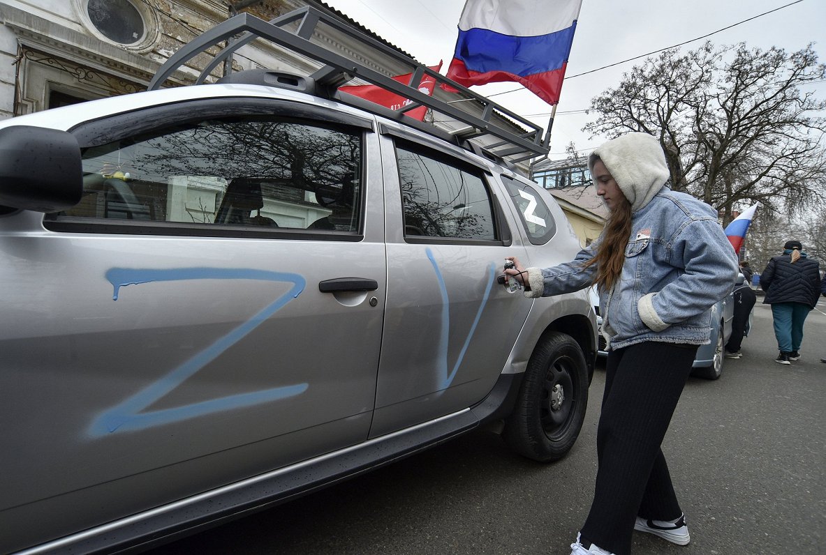 Krimas pilsētā Simferopolē meitene uz automašīnas uzkrāso Krievijas agresiju simbolizējošos Z un V b...