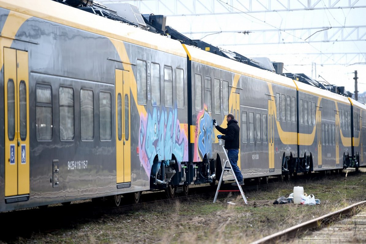 Rīgā, Vagonu depo, tīra jauno elektrovilcienu, kas apzīmēts ar grafiti.