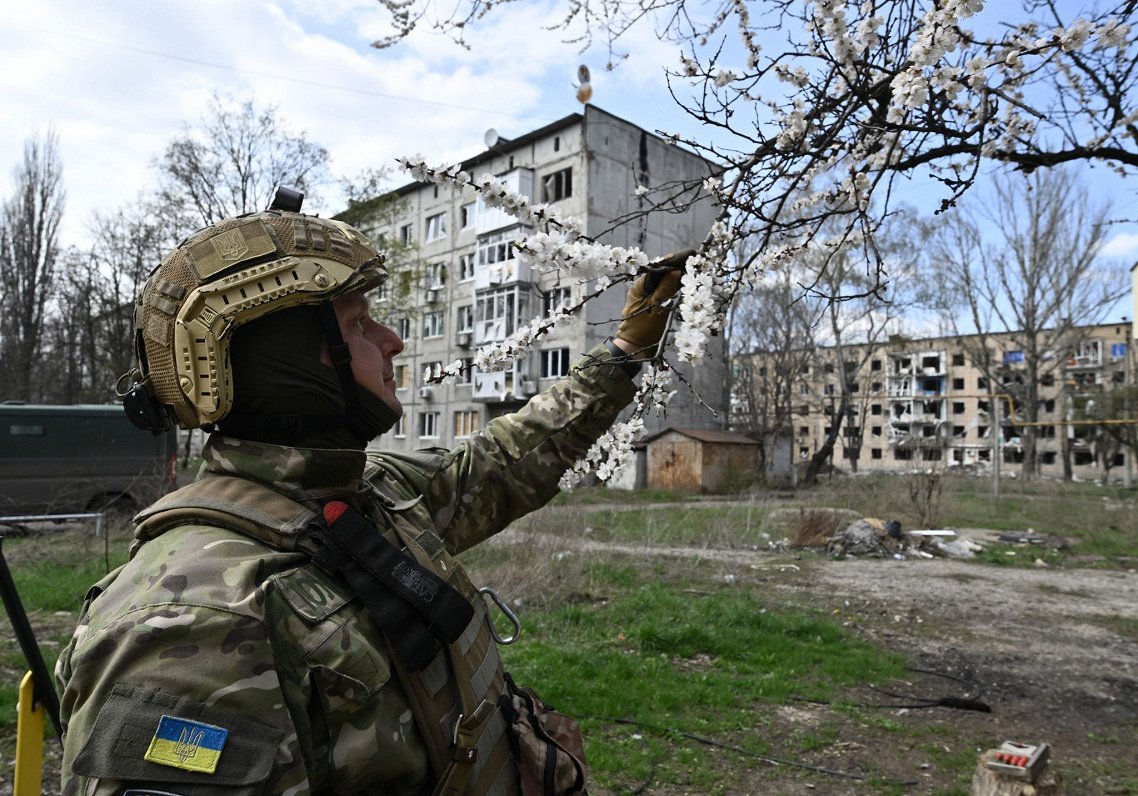 Ukrainas armijas karavīrs aplūko ziedošu koku Doneckas apgabala pilsētā Avdijivkā