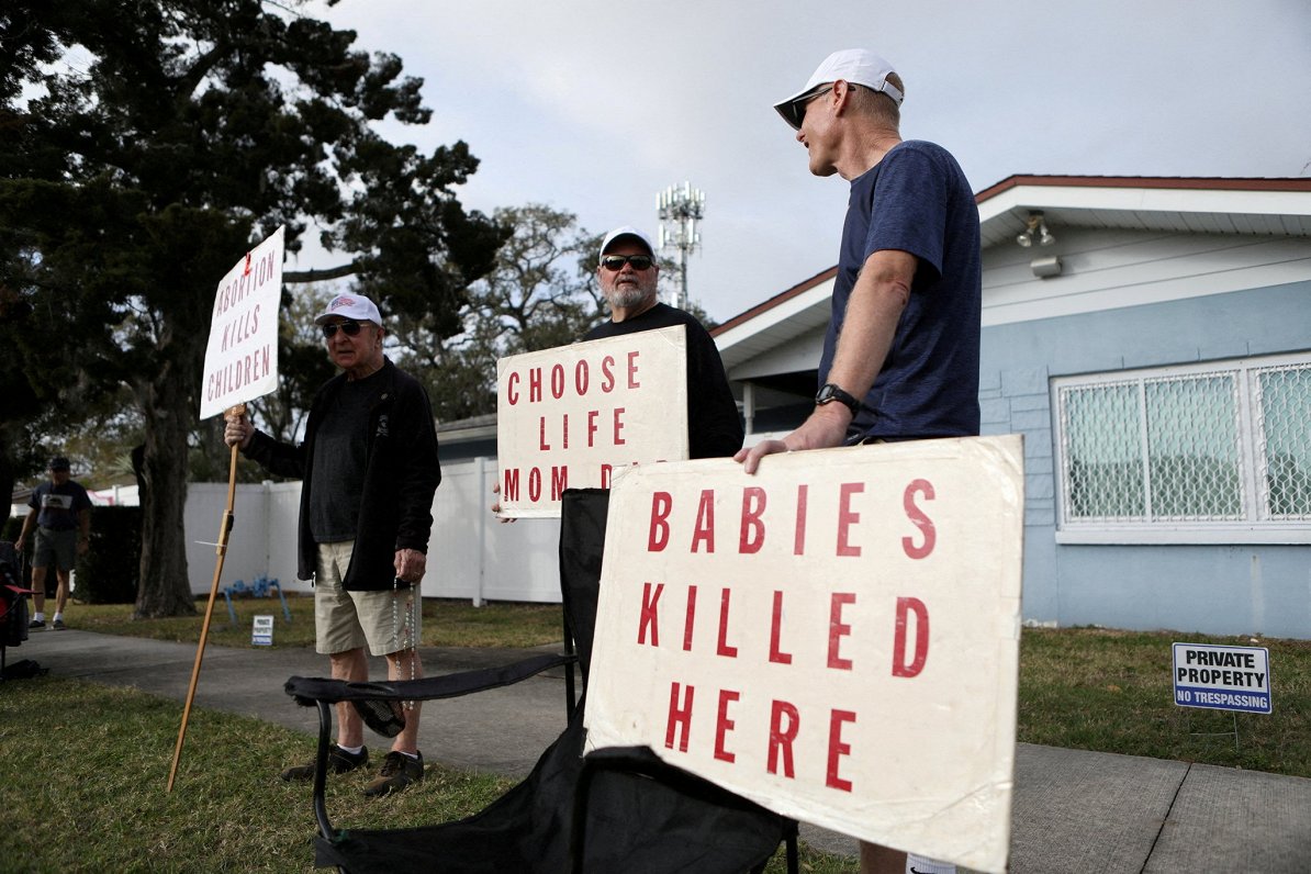 Protestētāji pie klīnikas Floridā, kur tiek veikti aborti. Plakāts vēsta &quot;Šeit nogalina bērnus&...