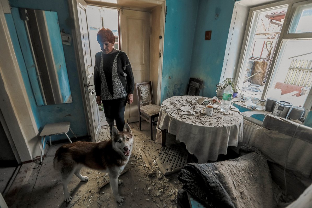 Ukrainas pilsētā Hersonā sieviete ar suni mājā, kas cietusi Krievijas sarīkotā apšaudē