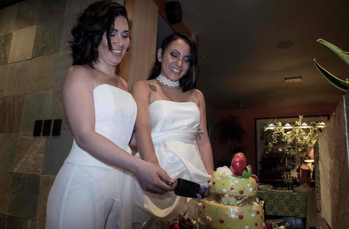 Kostarikā lesbiešu pāris griež kāzu torti. Kostarikā viendzimuma laulības tika legalizētas 2020. gad...