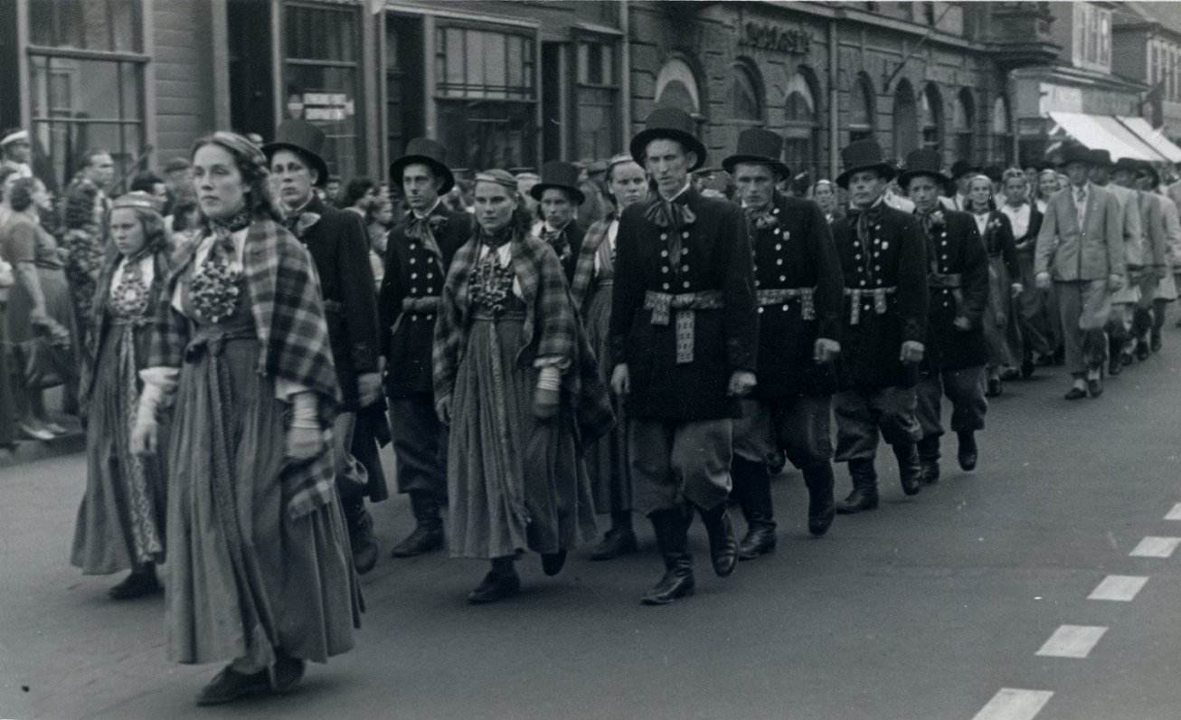Basu deju kolektīvs gājienā Rīgā, Ļeņina ielā. Priekšplānā – kolektīva vadītāja Dzidra Rasmane. 1948...