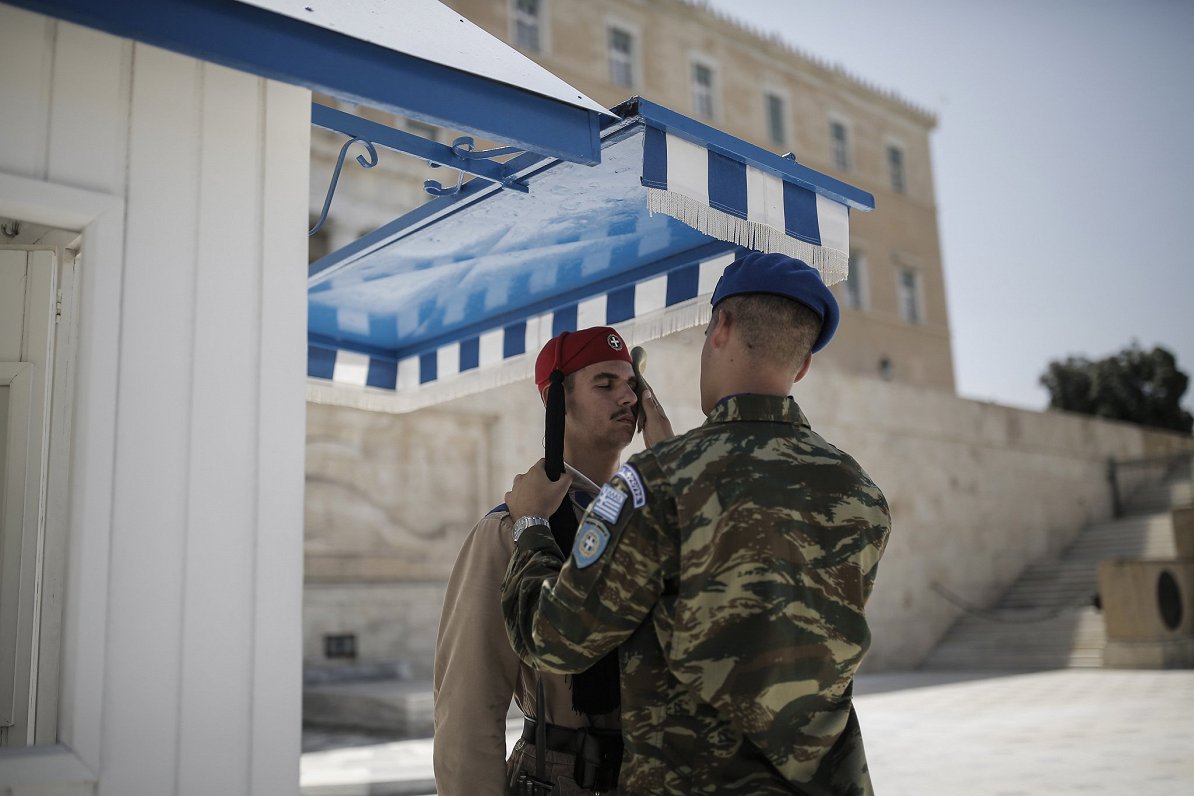 Grieķijas galvaspilsētā Atēnās karavīrs palīdz noslaucīt sviedrus godasardzes karavīram. Atēnās gais...