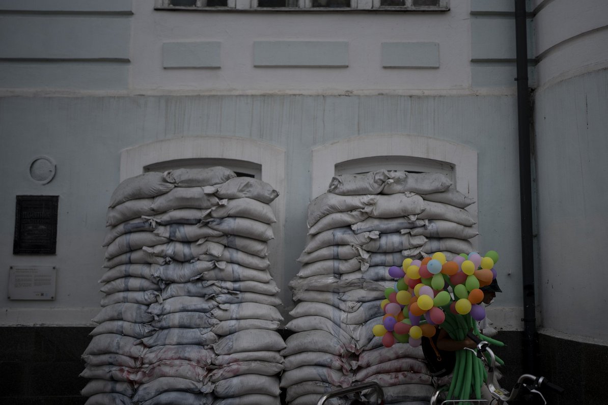 Мужчина продает воздушные шары у окон старого дома в Киеве, 26 августа 2023 года