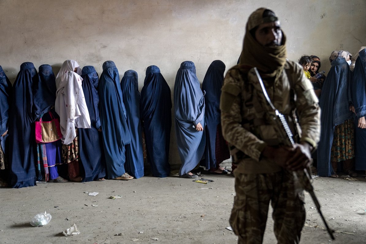 Talibu kaujinieks apsargā afgāņu sievietes, kas stāv rindā pēc pārtikas