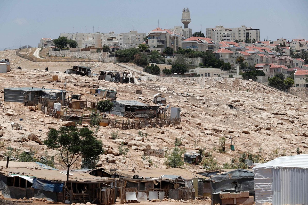Beduīnu teltis un pussabrukušie mājokļi ieprietim Izraēlas izveidotajām ebreju apmetnēm Rietumkrastā