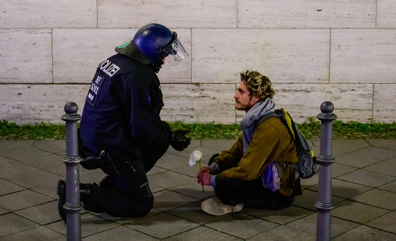 Vācijas policists sarunājas ar protestētāju, kurš Berlīnē piedalās akcijā palestīniešu atbalstam