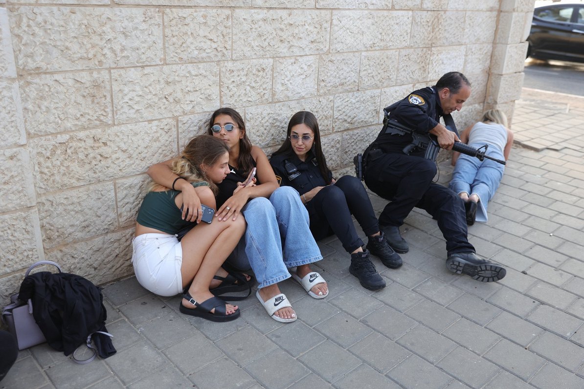 Izraēlas pilsētā Telavivā iedzīvotāji reaģē uz trauksmes sirēnu, kas brīdina par raķešu uzbrukumu
