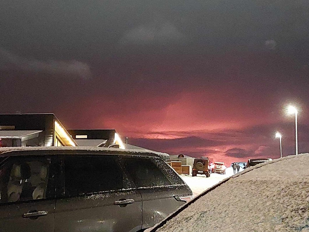 Vulkāna izvirduma iekrāsotās sārtās debesis Koupavoguras pilsētiņā Islandē
