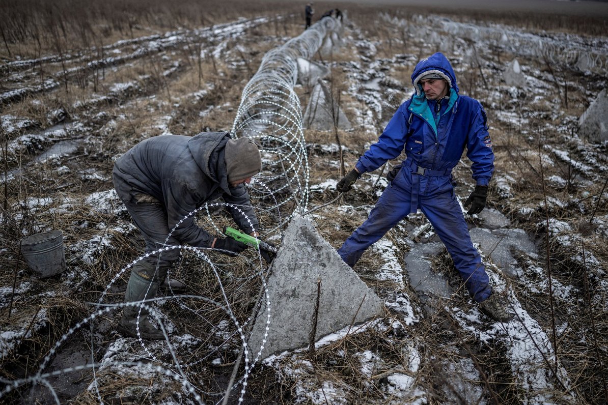Рабочие устанавливают колючую проволоку возле линии фронта в Харьковской области. Снимок сделан 25.1...