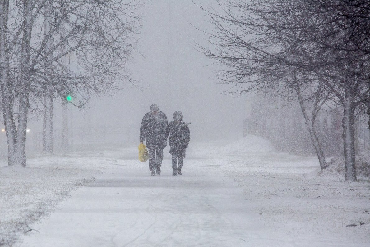 Cilvēki uz ielas sniegputeņa un vētras laikā.