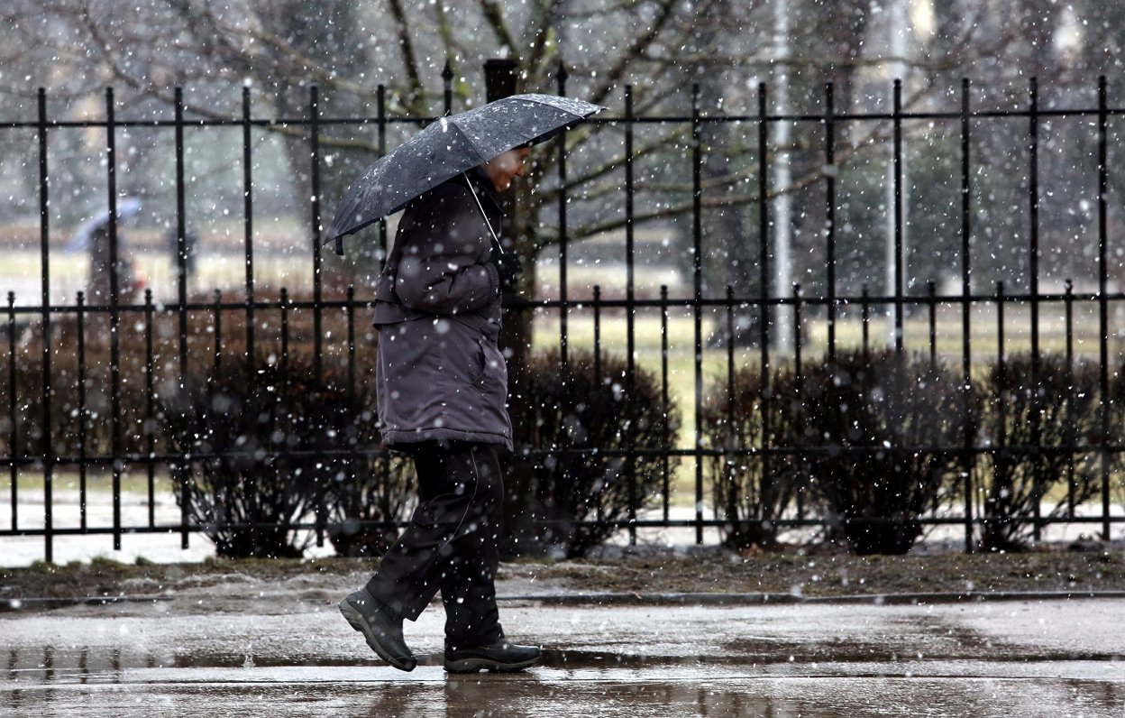 Sieviete ar lietussargu slapja sniega laikā.