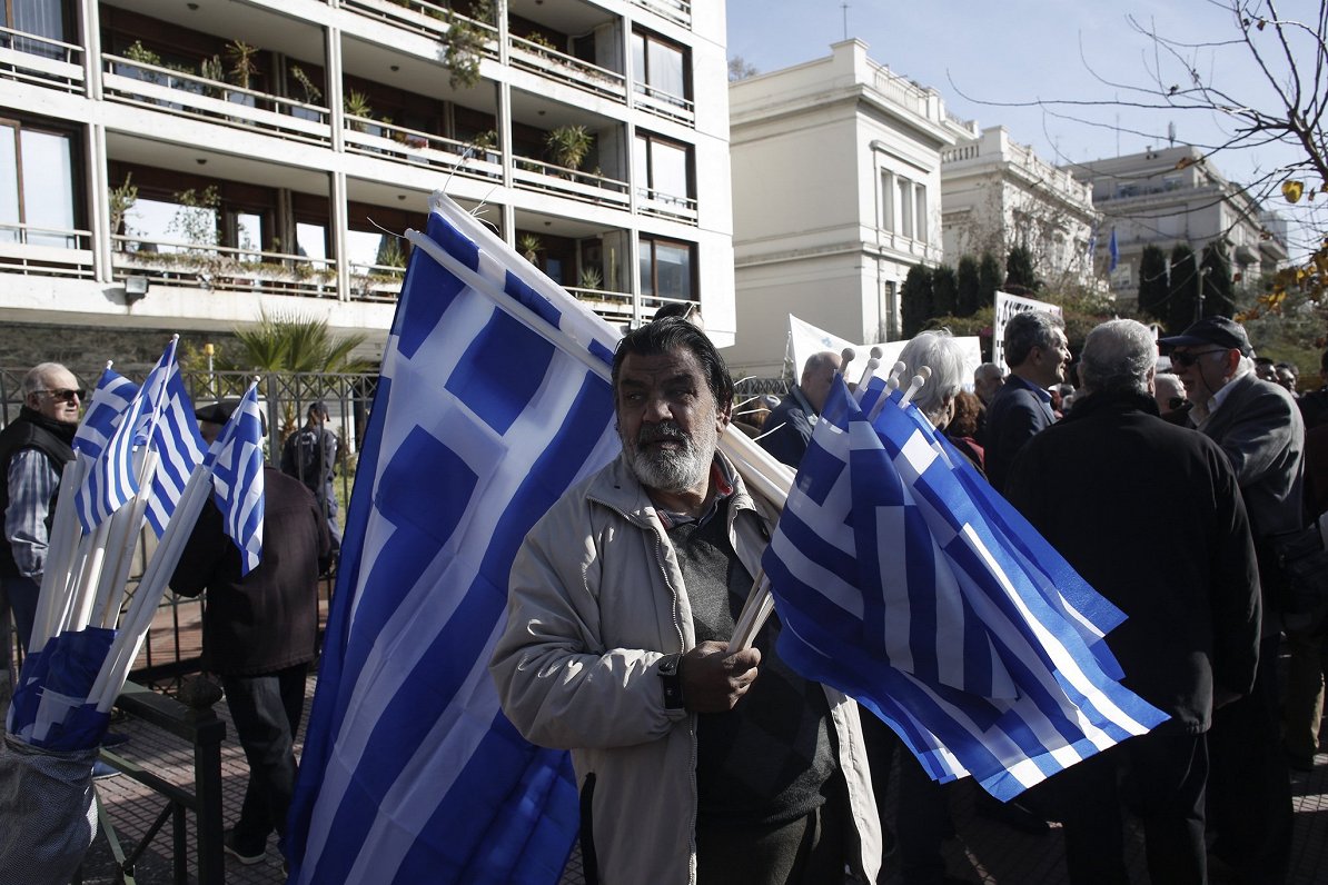 Ielu pārdevējs tirgo Grieķijas karogus Atēnās